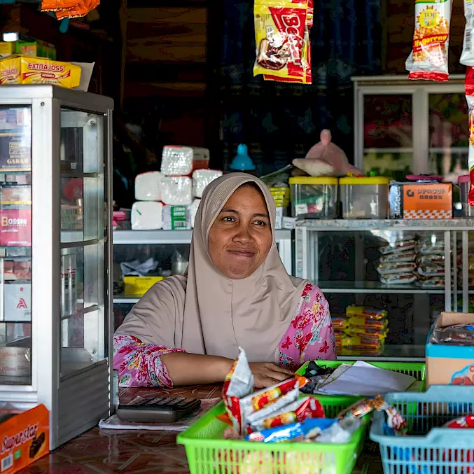 Hauptbild: Die lokale Unternehmerin betreibt ihren Kiosk mithilfe von BOS-Mikrokrediten und trägt zur wirtschaftlichen Entwicklung und Gemeinschaftsstärkung in Indonesien bei. © Andrew Suryono | BOSF | BOS Schweiz